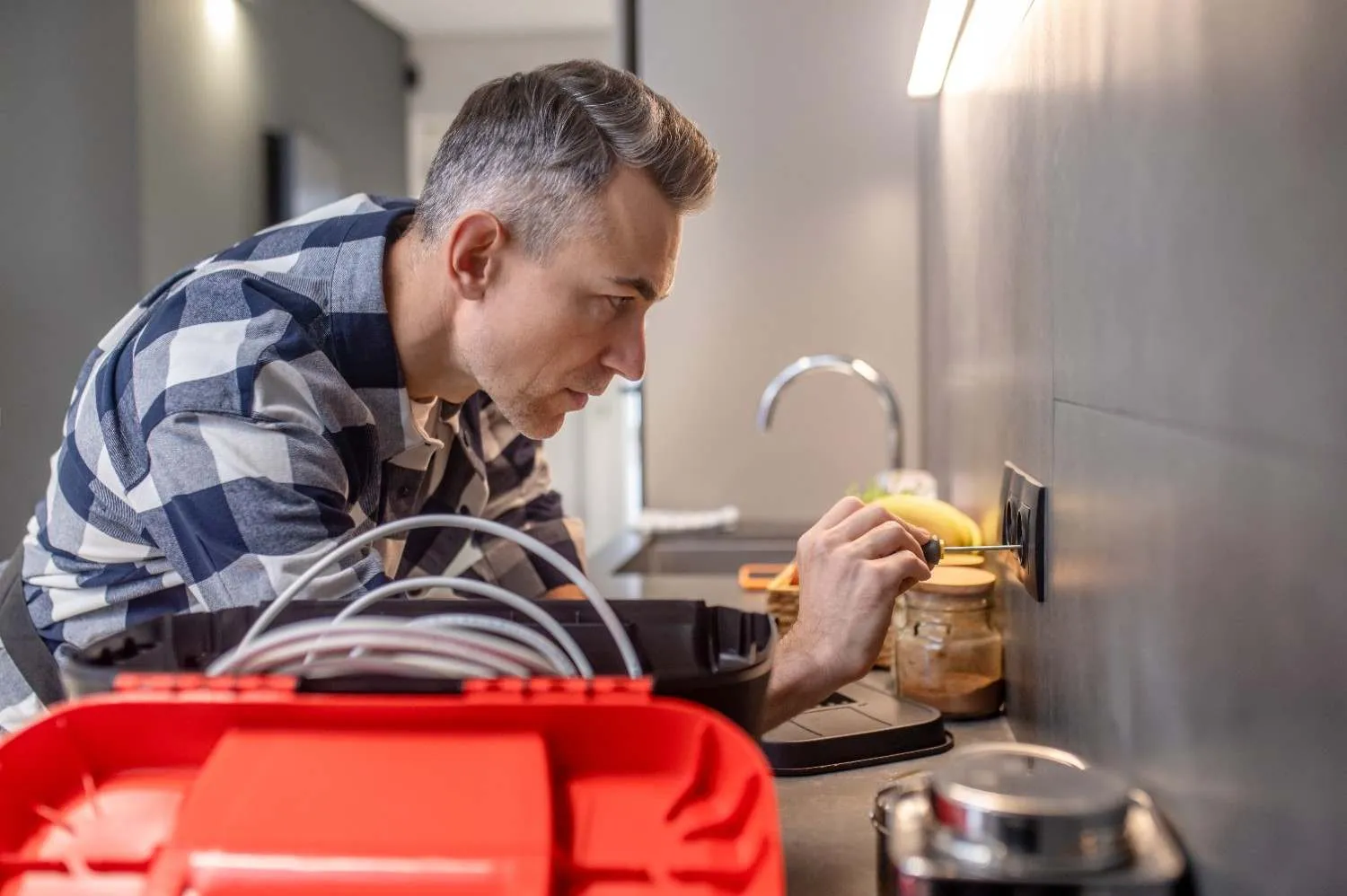 Technician checking a kitchen outlet with a screwdriver
